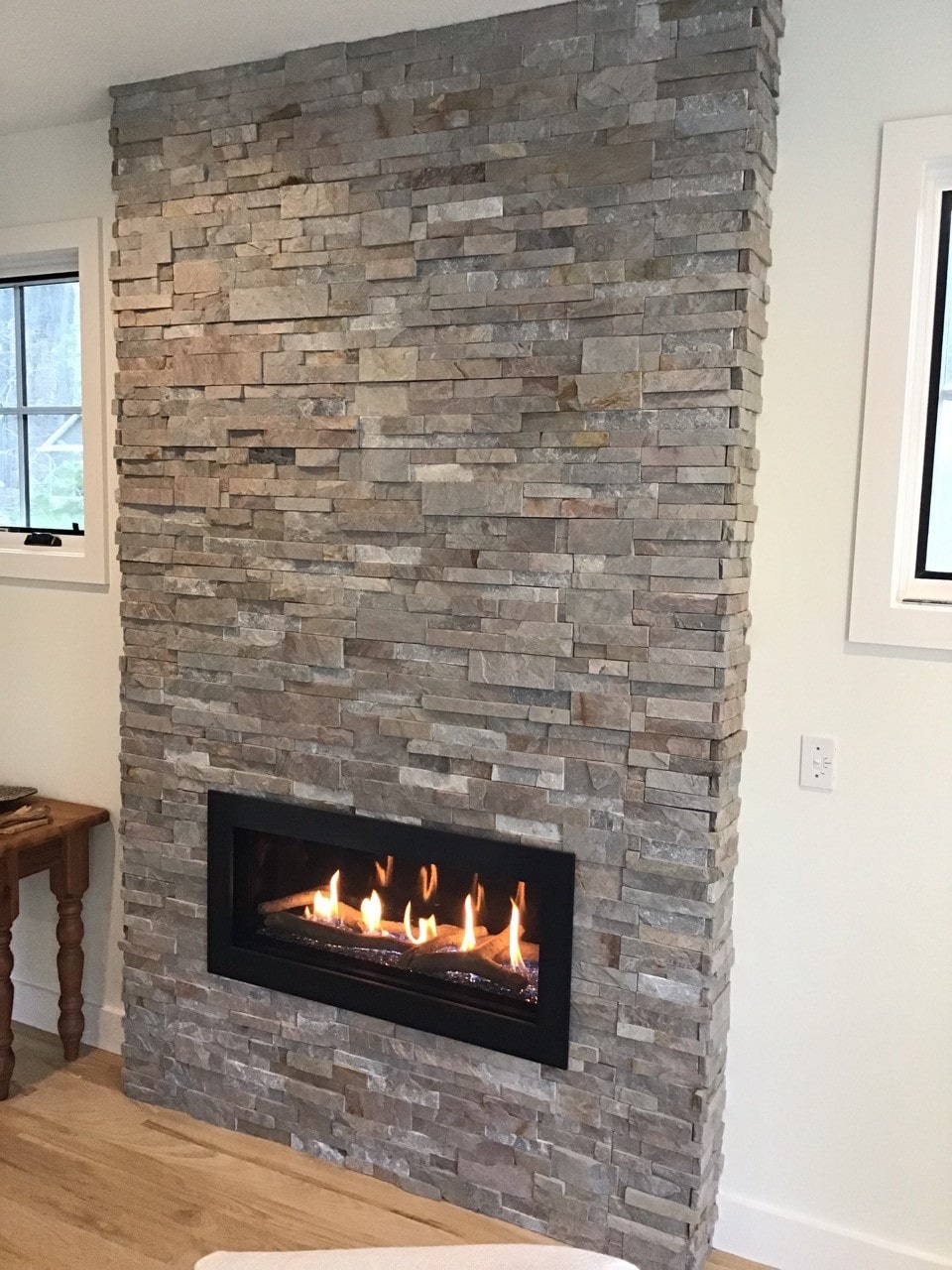 Stacked Stone fireplace clad floor to ceiling in Norstone Sierra XLX Silver Grey color